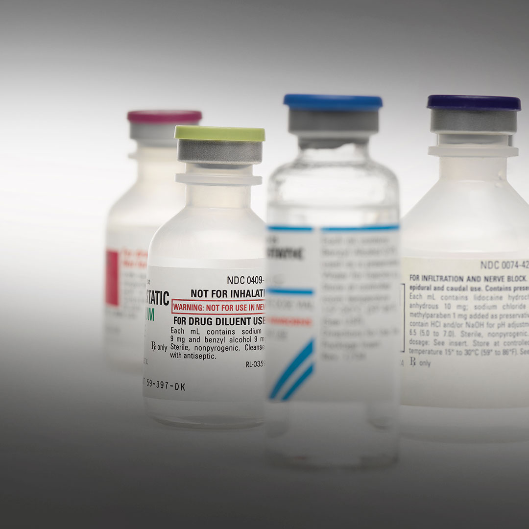 Four labeled medical vials with colorful caps, two in sharp focus and two blurred, indicating drug or medication use.