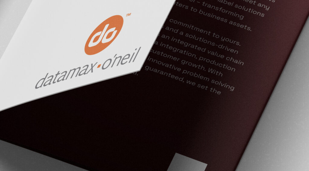 Partially opened brochure showing Datamax-O’Neil orange and white logo on cover and text on maroon inner page.