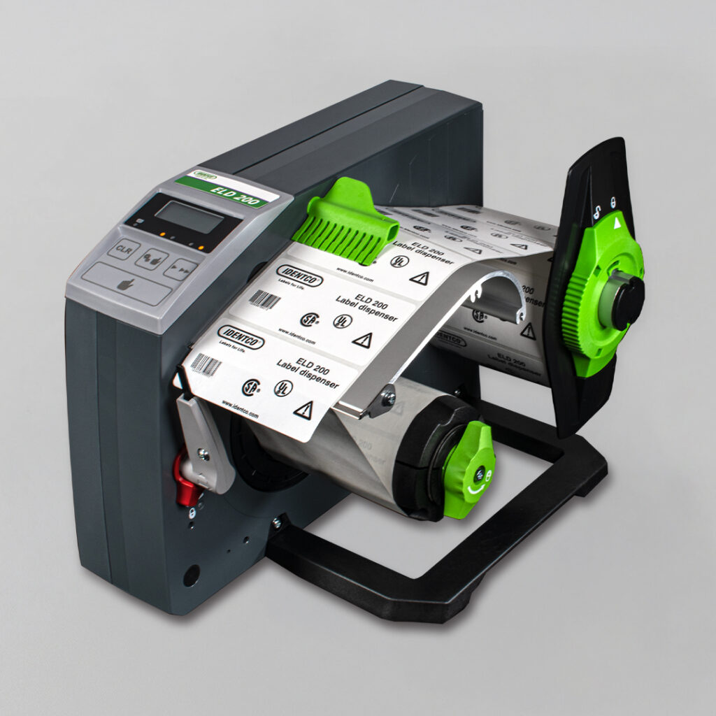 Gray and black label printer with green accents, open to display label roll, printing barcode adhesive labels with symbols.