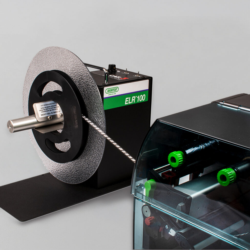 Close-up of CENTURY ELR 100 industrial label rewinder beside a label printer with green parts on a gray background.