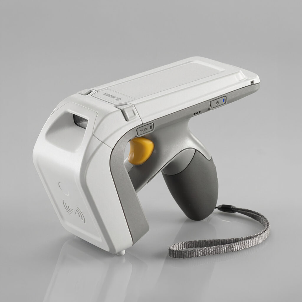 Handheld barcode and RFID scanner with gray and white body, yellow trigger, gray handle, wrist strap on light gray surface.