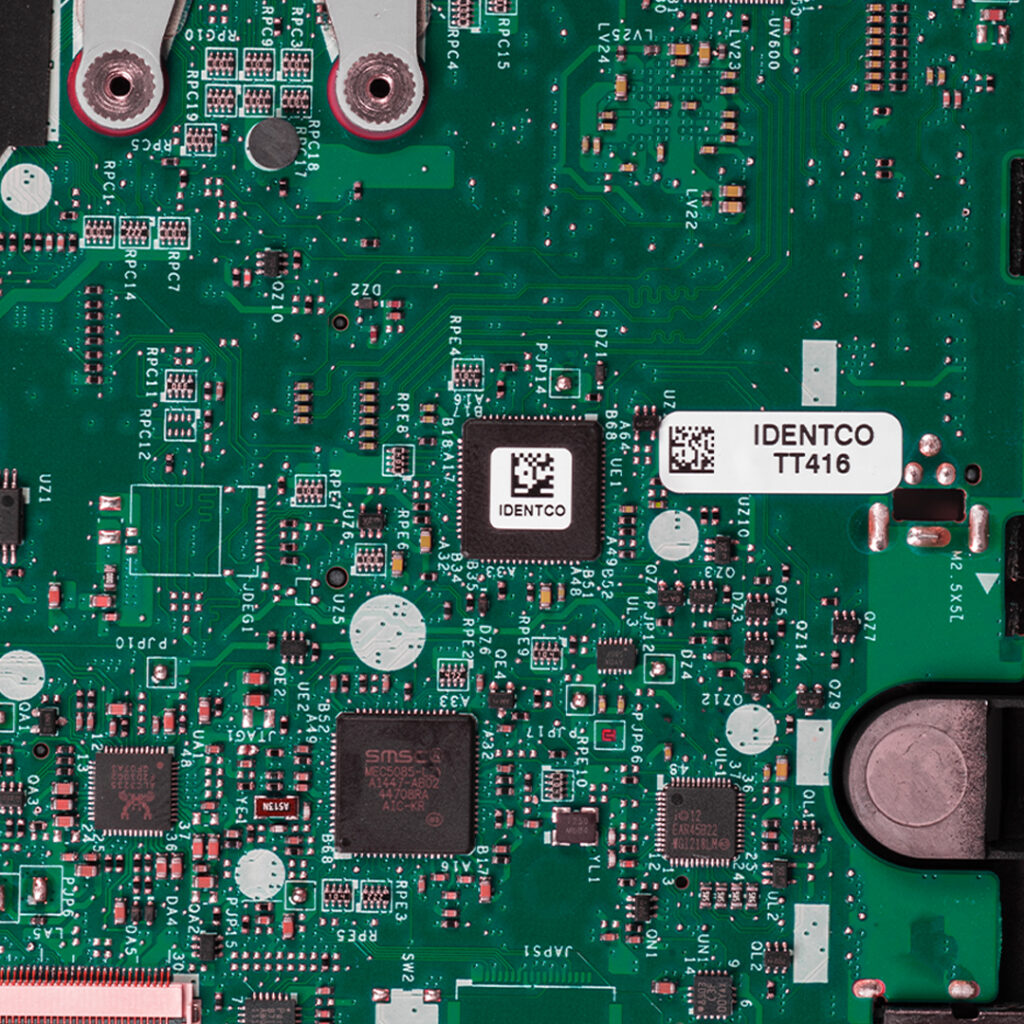 Green printed circuit board with electronic components, chips, and a white barcode label marked IDENTCO TT416.