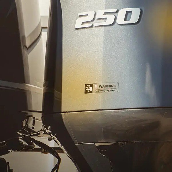 Close-up of metallic outboard boat motor showing 250 and a small security system warning label below the number.