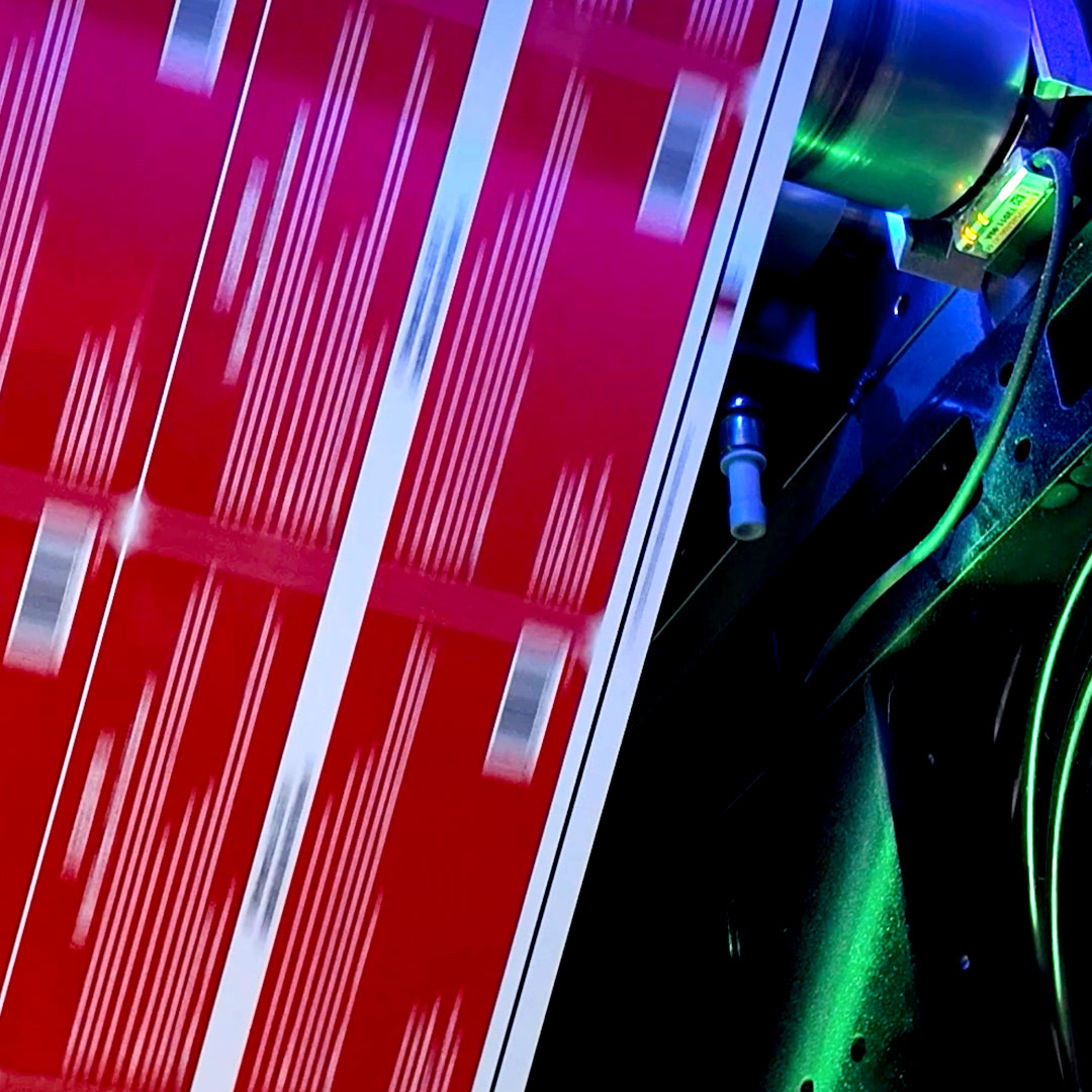 Printing machine outputting red labels with white stripes and barcodes, highlighted by blue and green lighting.
