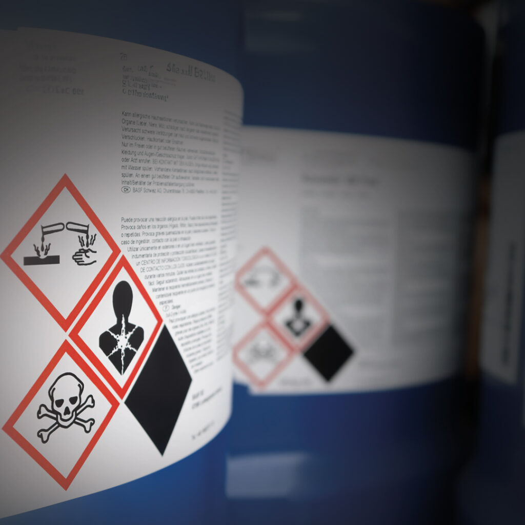 Chemical drum label with corrosive, toxic, and health hazard symbols plus safety and handling instructions in text.