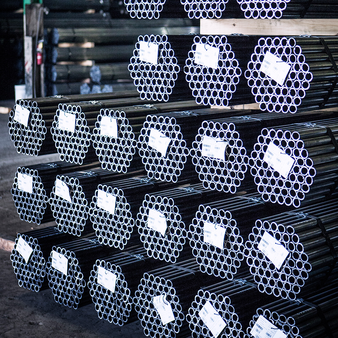 Rows of labeled metal pipe bundles neatly stacked inside an industrial warehouse.