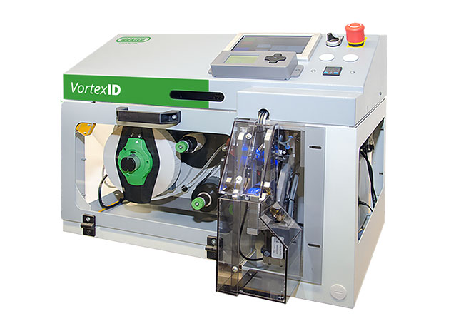 VortexID label printer with touchscreen, emergency stop, transparent front, visible components, gray with green, prints labels.