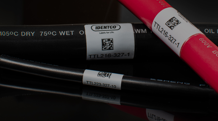 Close-up of three black and red cables with white barcode and IDENTCO brand labels on a glossy black surface.