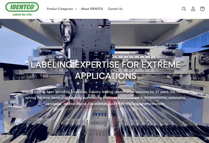 High-tech factory labeling machine with IDENTCO logo, navigation menu, and text: LABELING EXPERTISE FOR EXTREME APPLICATIONS.