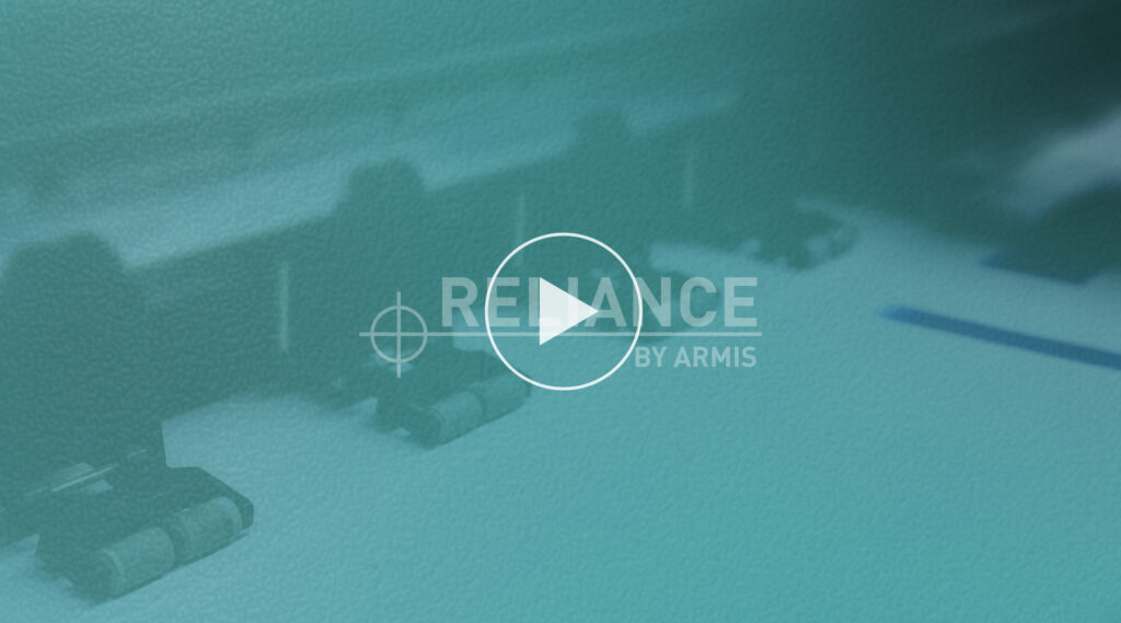 Blurred close-up of a printer or copier with RELIANCE BY ARMIS text and play button icon on blue-green tinted background, signaling video.