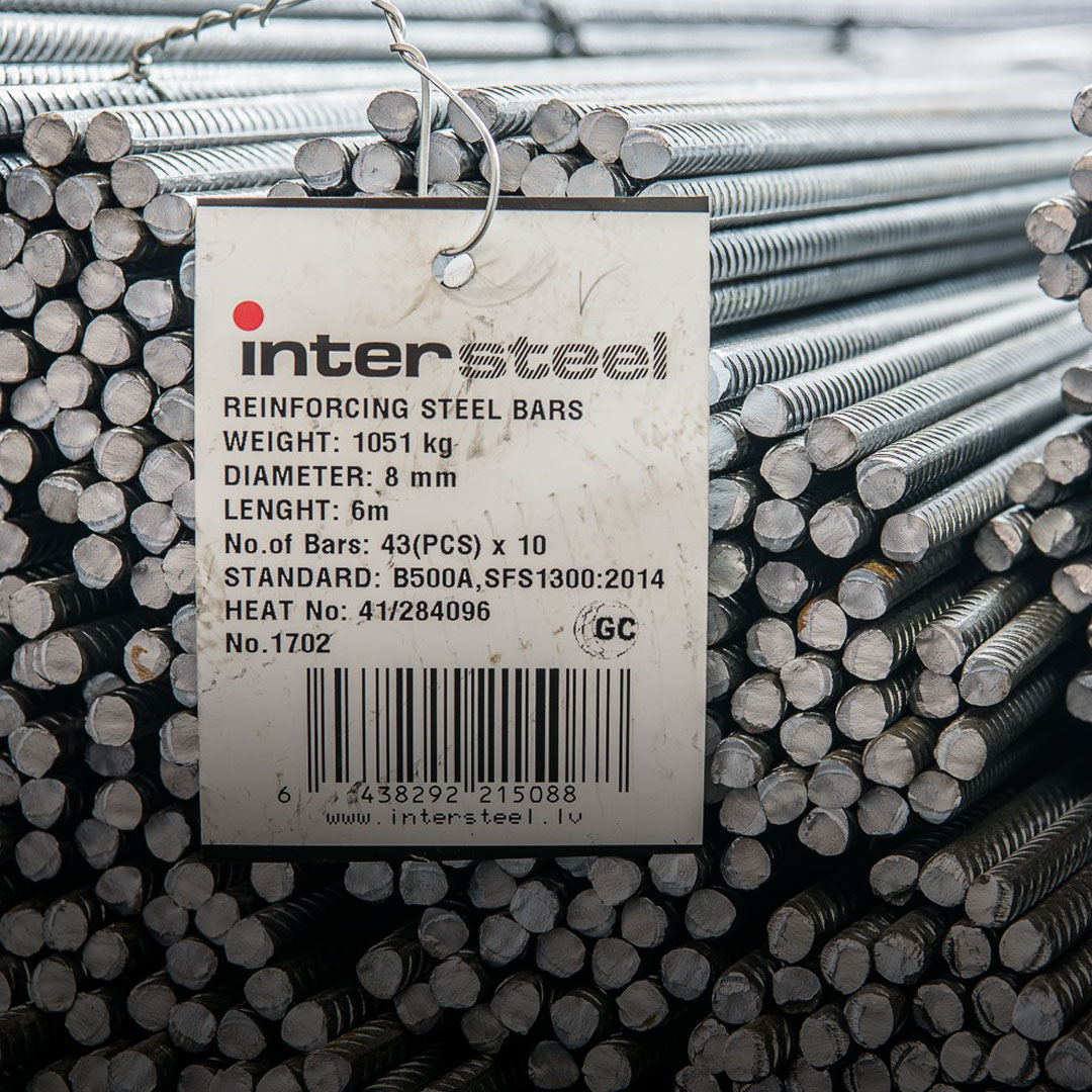 Stacked steel rebars with attached label displaying weight, diameter, length, quantity, standards, and barcode specifications.