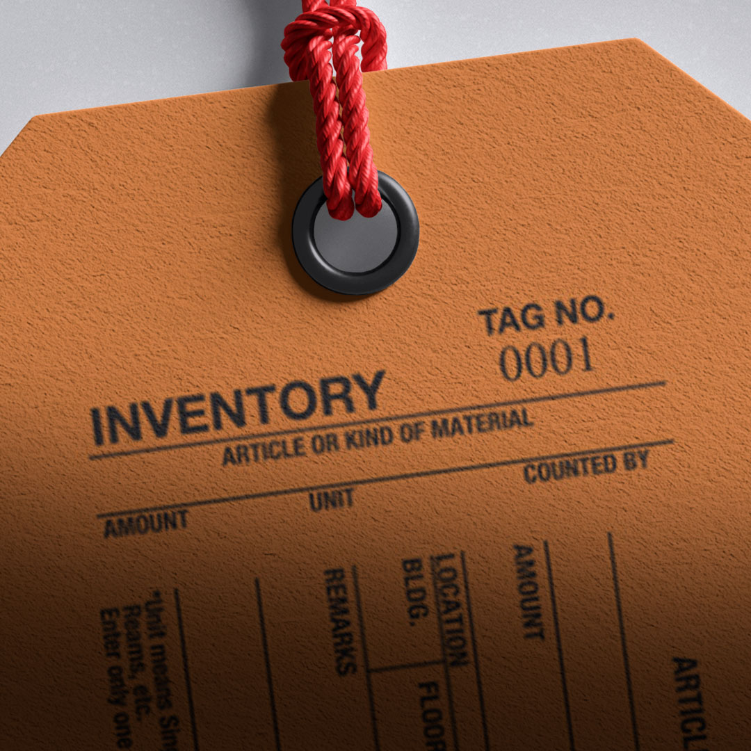 Close-up of a brown inventory tag with red string, black ring, bold INVENTORY and TAG NO. 0001, and blank fields for item details.