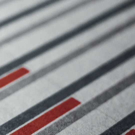 A close-up of parallel gray lines on a textured surface, with two of the lines highlighted in red, creating a pattern of contrast amid the otherwise monochromatic design.