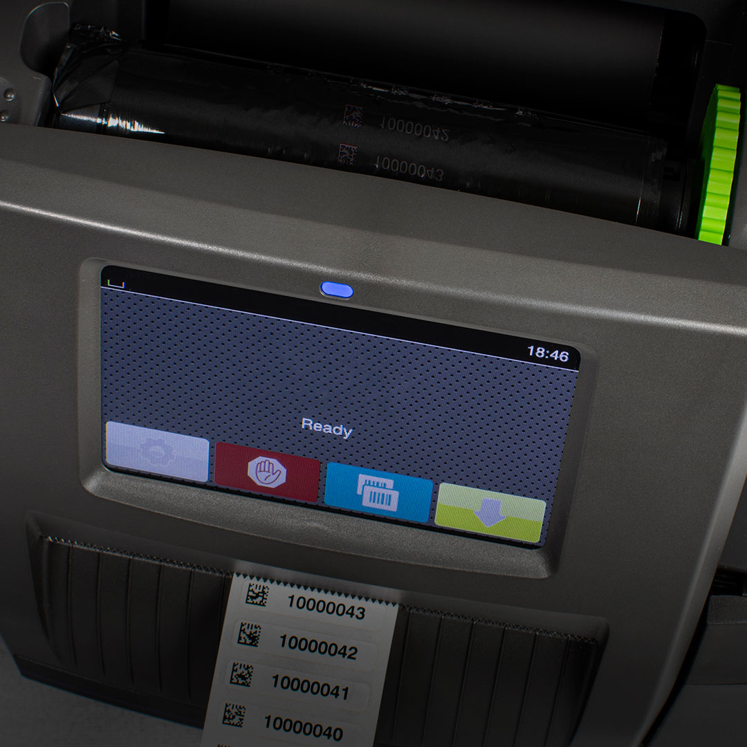 Label printer with touchscreen showing Ready, four colored buttons, and multiple barcode labels emerging from the bottom slot.