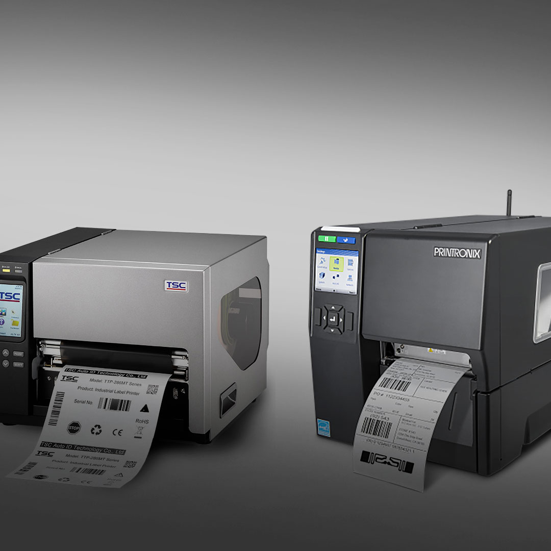 Silver TSC and black Printronix industrial label printers print barcode labels side by side on a gray gradient background.