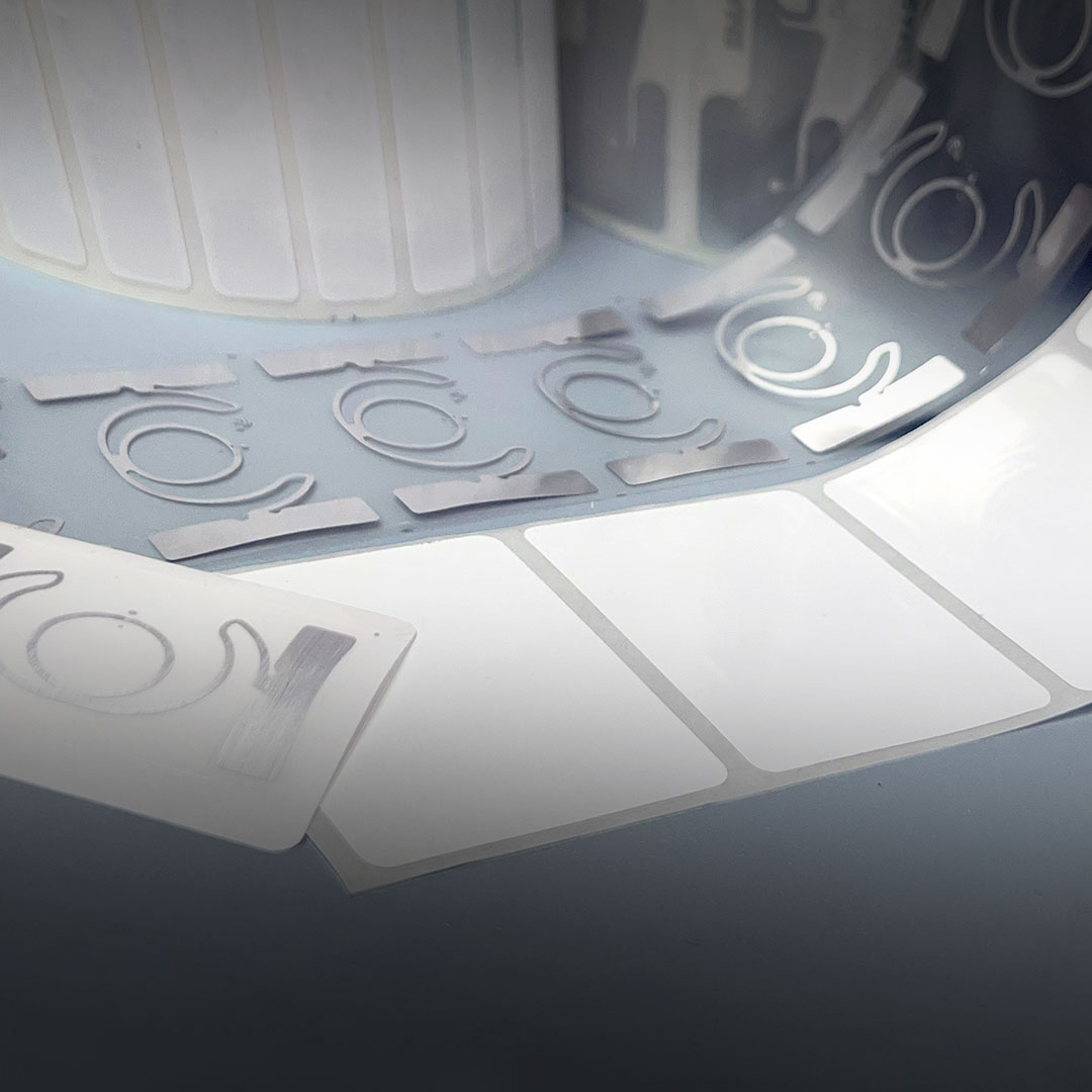 Close-up of RFID labels on a roll with blank white stickers and metallic antenna patterns for tracking and identification.