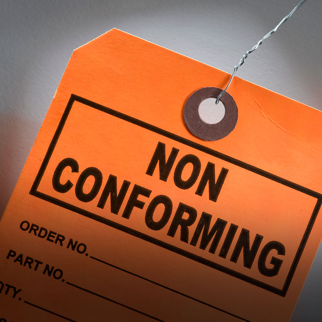 Orange tag with metal wire marked NON CONFORMING in bold, blank fields for order and part numbers, set against a neutral background.