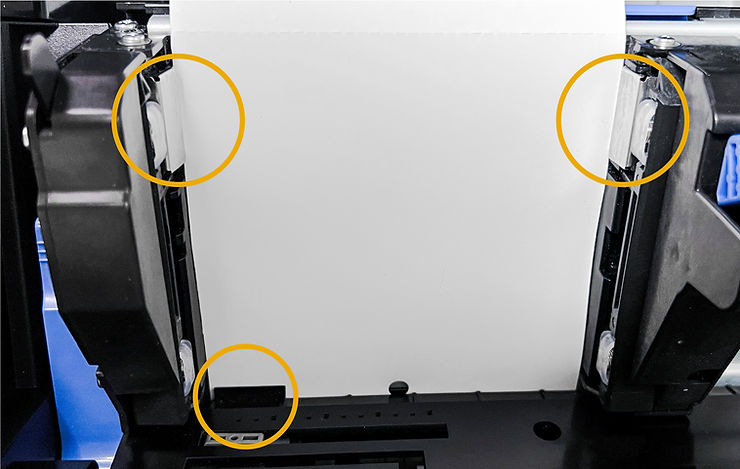 Close-up of printer paper feed with three yellow circles marking key parts on left, right, and bottom; paper partially inserted.