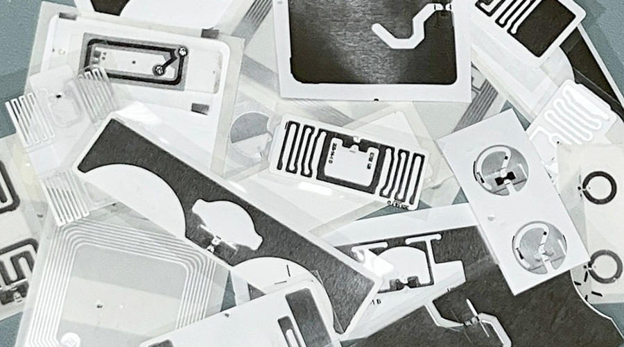 Rectangular electronic sensors scattered, featuring black and silver conductive patterns on white plastic, some with circular cutouts.