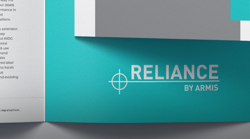 Close-up of a teal and white Reliance by Armis brochure featuring a crosshair logo printed on the cover.
