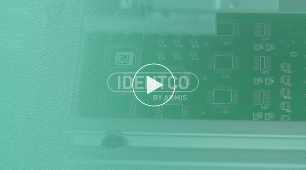 Green circuit board with electronic components, play button overlay, and IDENTCO BY AMMS text centered on the image.
