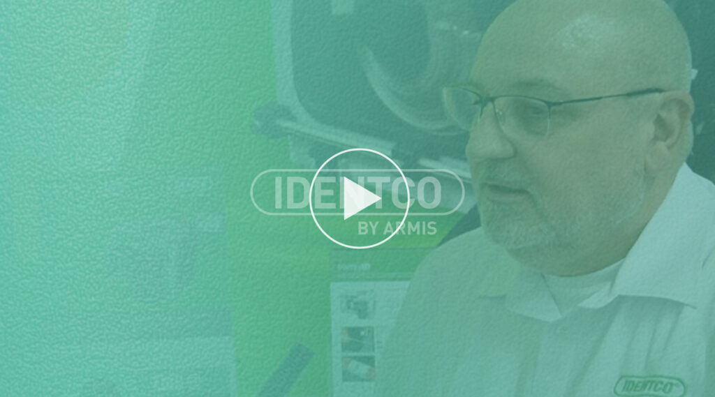 Bald man with glasses in IDENTCO logo shirt featured in video thumbnail with green overlay and centered play button.