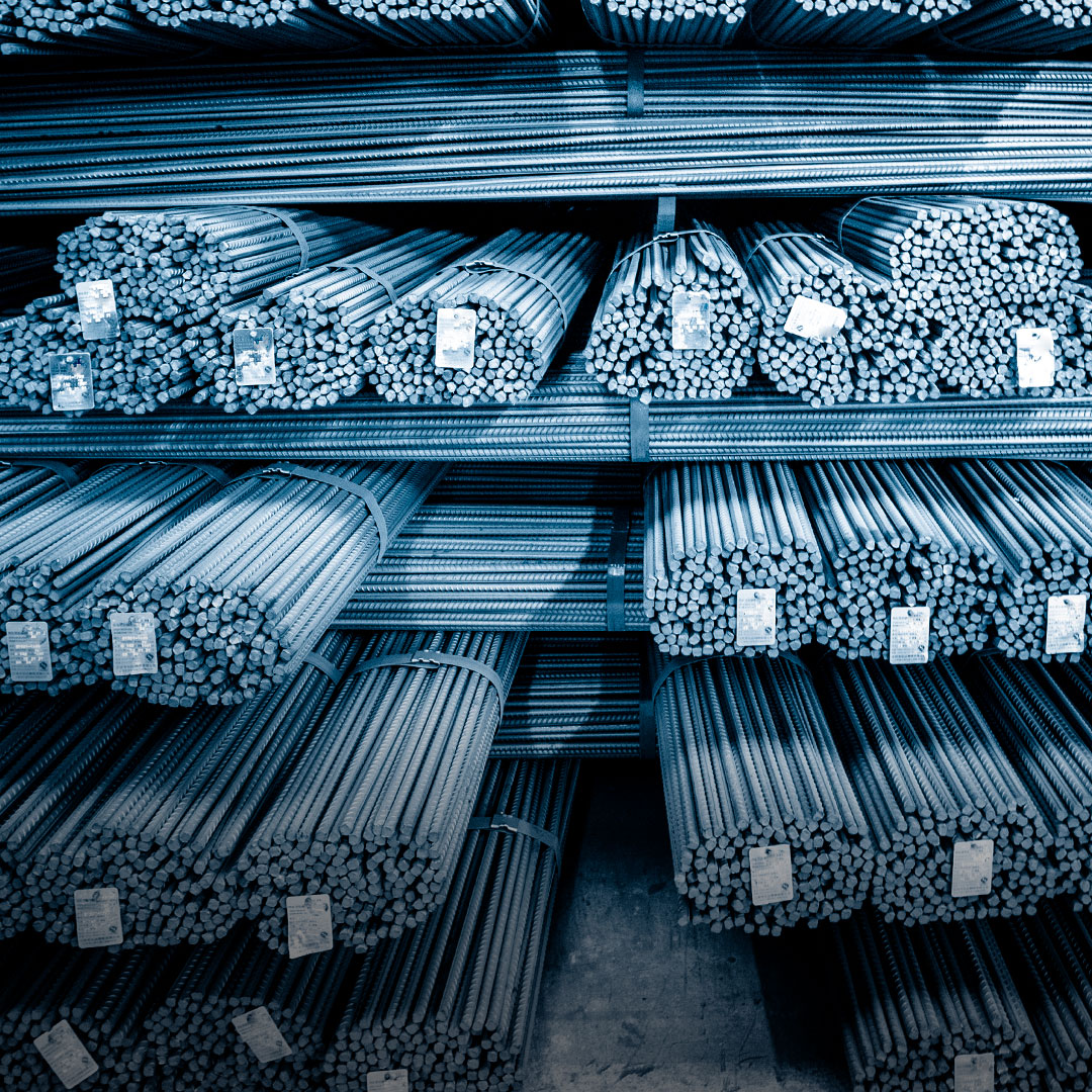 Steel rebars stacked and bundled with tags on industrial warehouse shelves, organized under a blue-toned light filter.