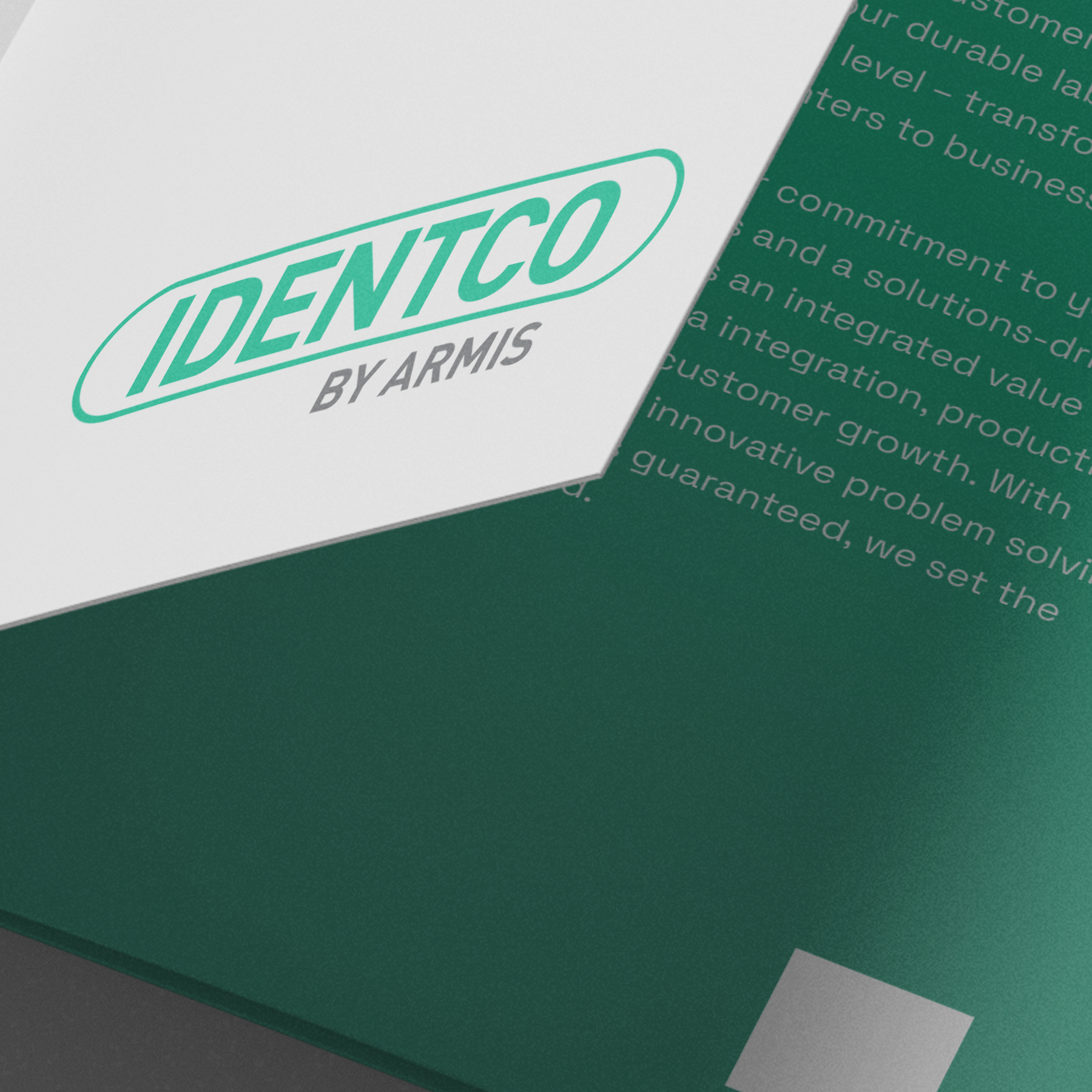 Close-up of two overlapping brochures, top one with IDENTCO BY ARMIS green and gray logo, bottom with white text on green background.